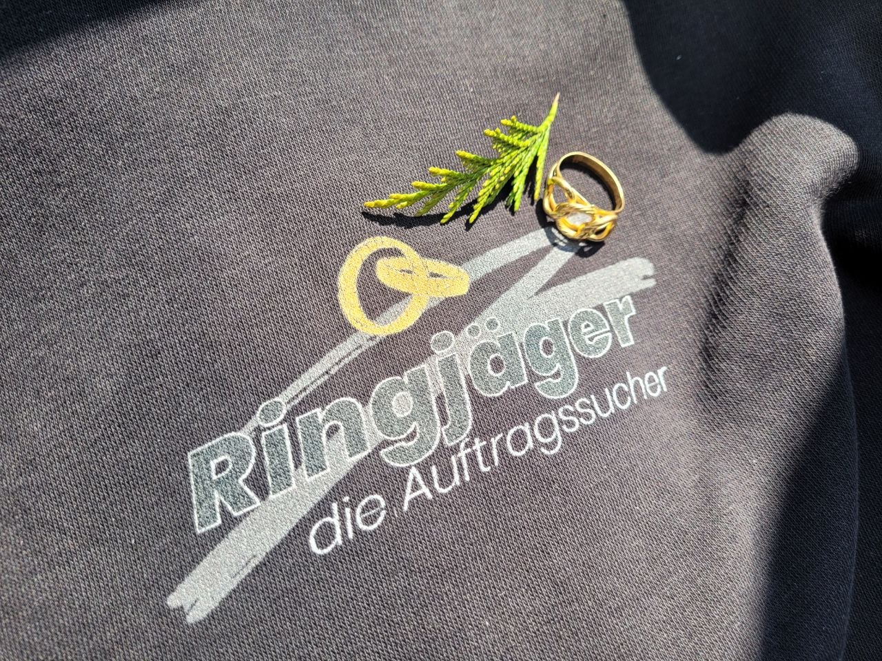 Zwei Mitglieder unseres Netzwerks im Garten, einer hält einen kleinen Ring zwischen den Fingern hoch.